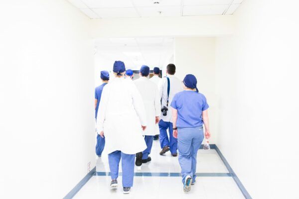 Healthcare workers working down a white corridor