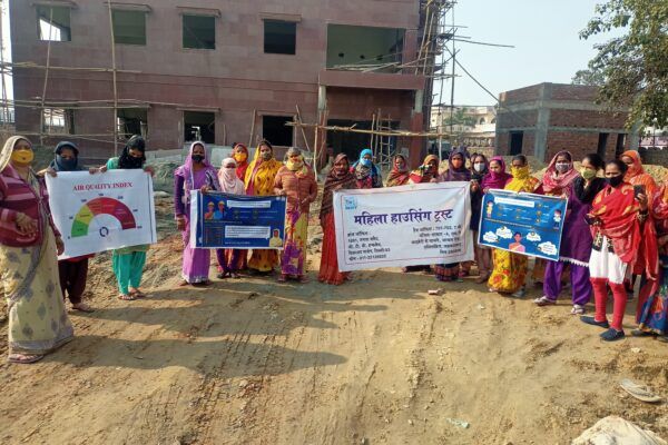 Group of women construction workers hold up air pollution awareness signs