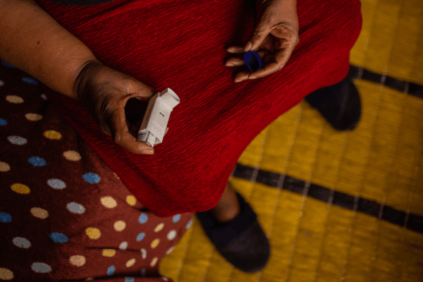 A woman shows the inhaler that she uses for asthma exacerbated by the coal mine a street away from her house in Clever, Witbank, Emalahleni, South Africa. Credit: Gulshan Khan / Climate Visuals